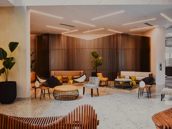 A bright hotel lobby with wooden panels and lounge seating