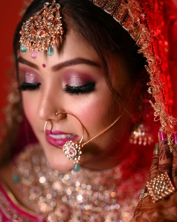 A bride in a red lehenga with gold jewellery and soft bridal makeup