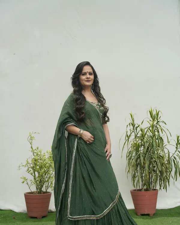 A woman in a green festive lehenga with a long dupatta