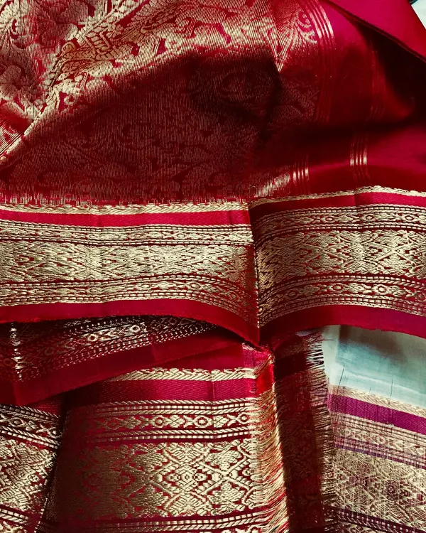 A red silk saree with a wide gold zari border